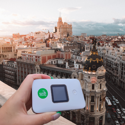 Madrid skyline view with a person holding a portable WiFi device in the foreground
