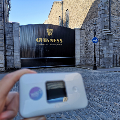 Person at Guinness St James's gate brewery gateway holding a portable WiFi device